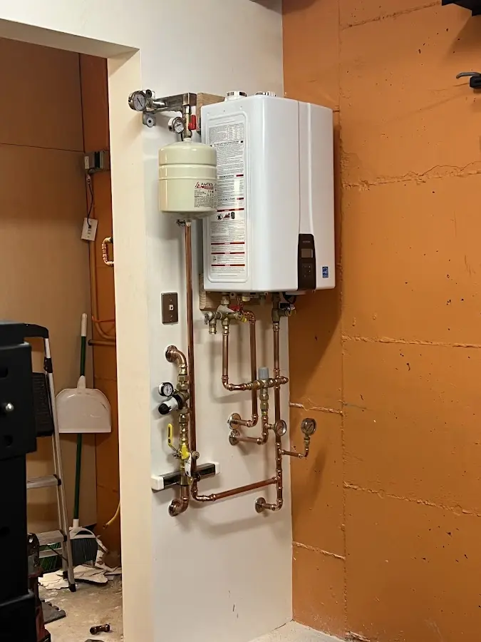 Plumbing technician inspecting water heater connections in Booneville